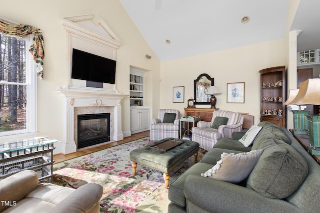 living room with light wood-type flooring, high vaulted ceiling, and built in shelves