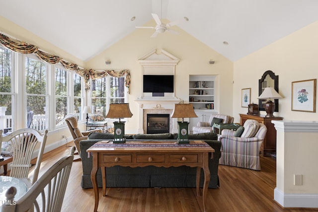 living room featuring ceiling fan, built in shelves, and wood-type flooring