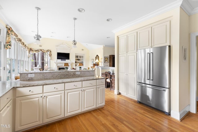 kitchen with open floor plan, high end fridge, hanging light fixtures, light wood finished floors, and a fireplace