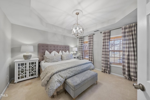 carpeted bedroom with a tray ceiling and a chandelier