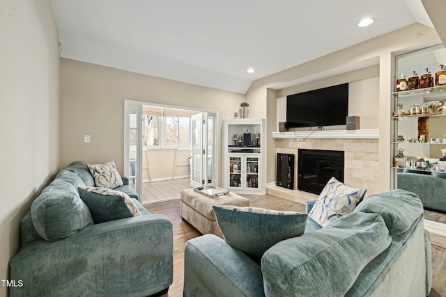 living room with lofted ceiling, hardwood / wood-style floors, and a tile fireplace