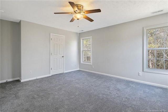 carpeted spare room featuring ceiling fan and a wealth of natural light