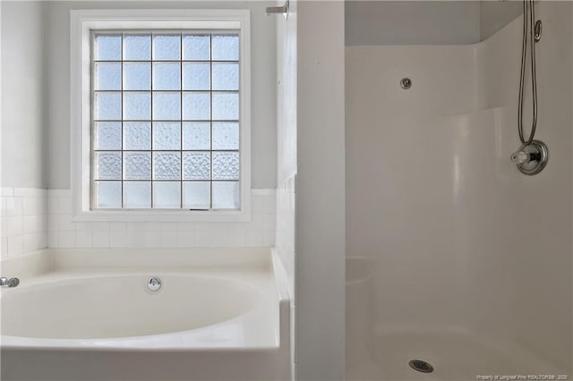 bathroom featuring a wealth of natural light and shower with separate bathtub