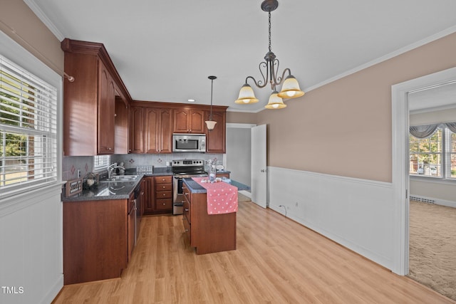 kitchen featuring an inviting chandelier, stainless steel appliances, a kitchen island, ornamental molding, and pendant lighting