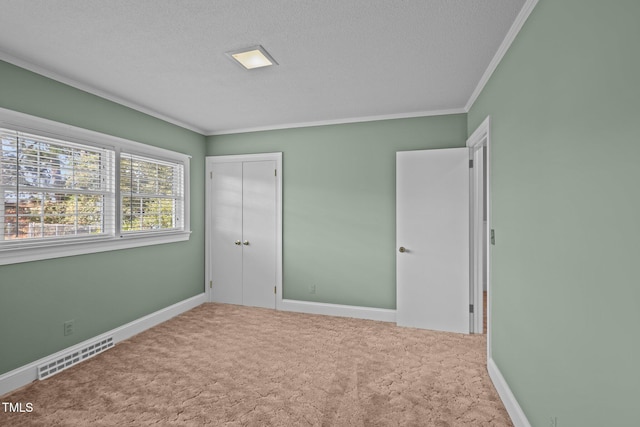 unfurnished bedroom featuring a textured ceiling, a closet, carpet, and crown molding