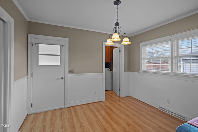 interior space with light hardwood / wood-style floors, washer / dryer, ornamental molding, and an inviting chandelier