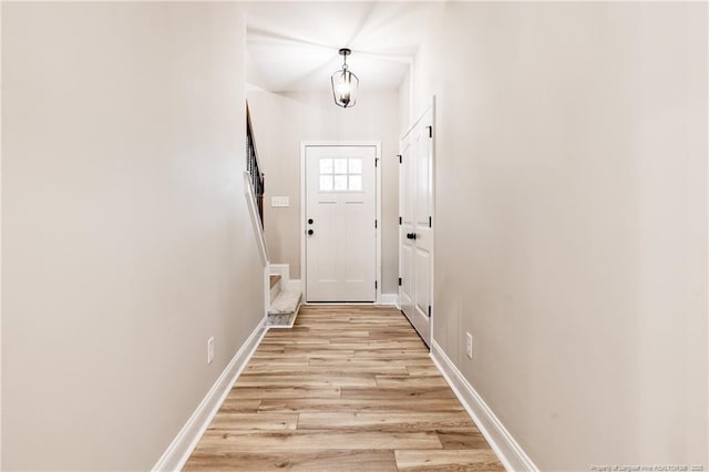 doorway to outside featuring an inviting chandelier and light hardwood / wood-style floors