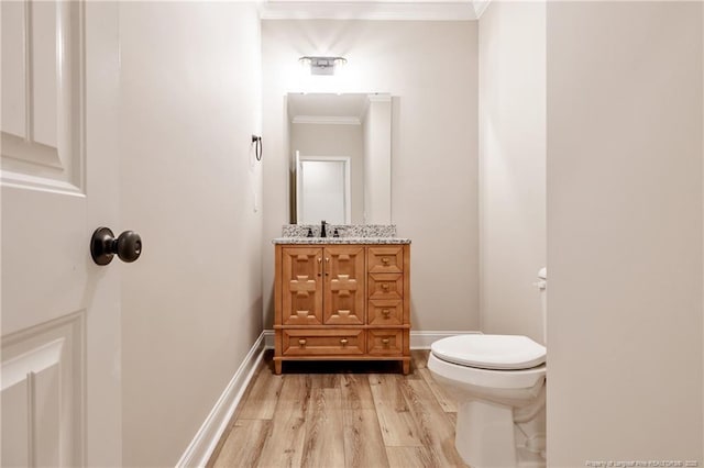 bathroom with toilet, crown molding, hardwood / wood-style flooring, and vanity