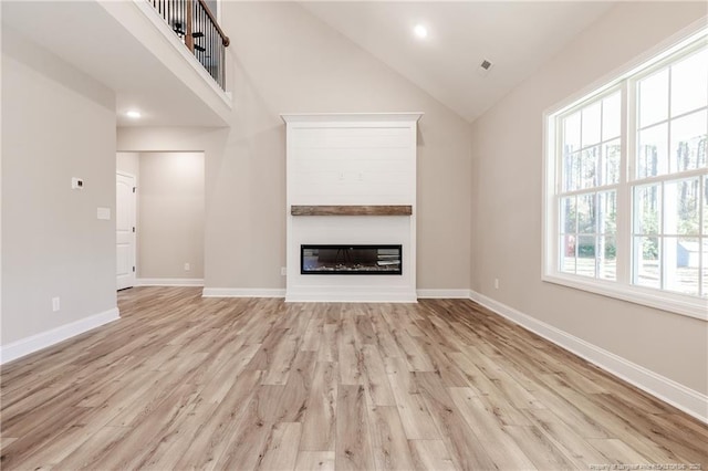 unfurnished living room featuring light wood-type flooring, a wealth of natural light, and high vaulted ceiling