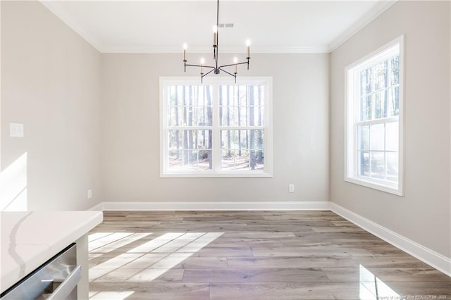 unfurnished dining area featuring a wealth of natural light, crown molding, a chandelier, and light hardwood / wood-style floors