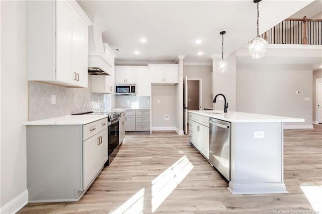 kitchen with pendant lighting, a center island with sink, sink, white cabinetry, and stainless steel appliances