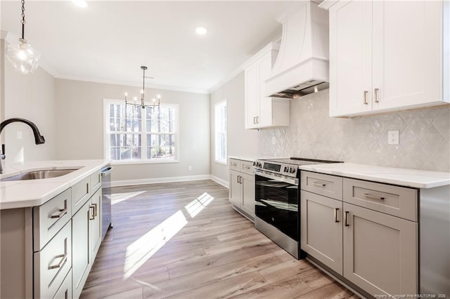 kitchen with pendant lighting, stainless steel appliances, premium range hood, sink, and crown molding