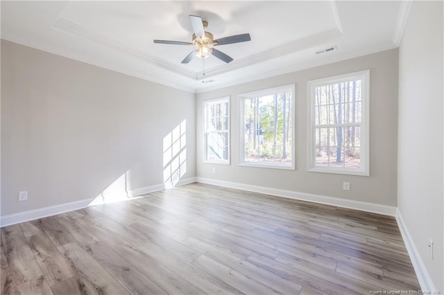 unfurnished room with light wood-type flooring, ceiling fan, ornamental molding, and a tray ceiling