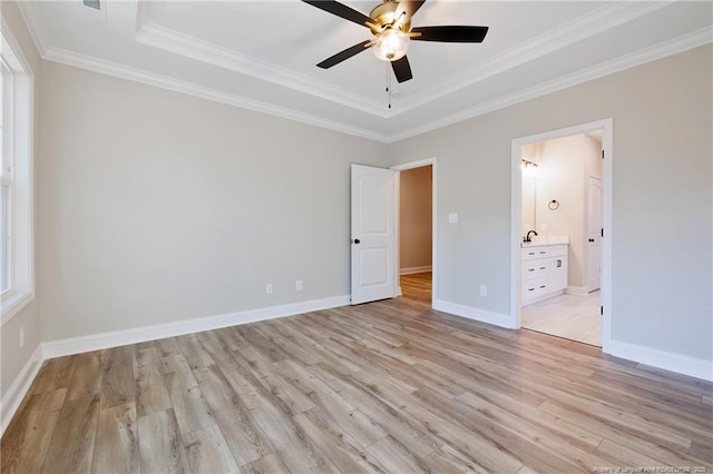 unfurnished bedroom with ceiling fan, ensuite bathroom, a tray ceiling, and crown molding