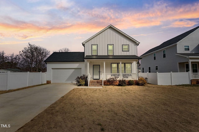 modern inspired farmhouse with covered porch, a garage, and a yard