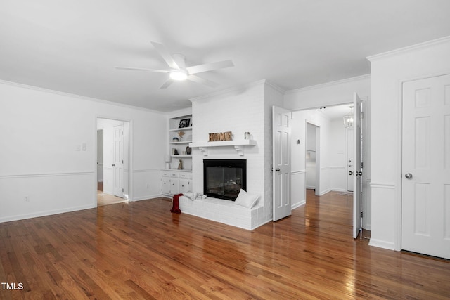 unfurnished living room featuring hardwood / wood-style floors, built in shelves, a fireplace, and ceiling fan