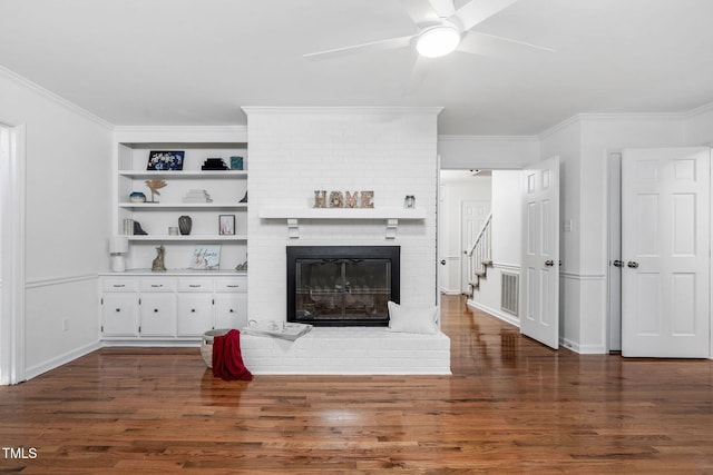 living room featuring crown molding, a fireplace, dark hardwood / wood-style flooring, and ceiling fan