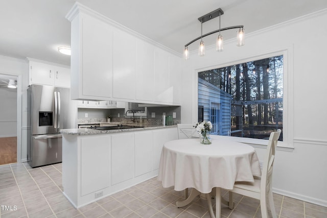 kitchen featuring decorative light fixtures, white cabinetry, stainless steel fridge with ice dispenser, crown molding, and light stone countertops