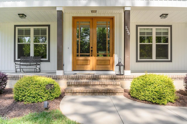 view of exterior entry featuring french doors and a porch