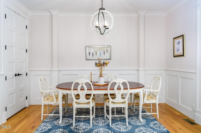 dining space featuring ornamental molding, hardwood / wood-style floors, and an inviting chandelier