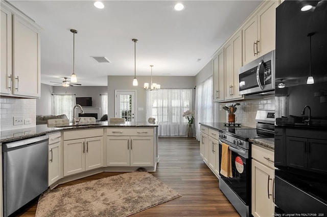 kitchen featuring ceiling fan with notable chandelier, sink, backsplash, and appliances with stainless steel finishes