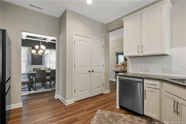 kitchen featuring dark stone countertops, stainless steel dishwasher, decorative backsplash, an inviting chandelier, and white cabinetry