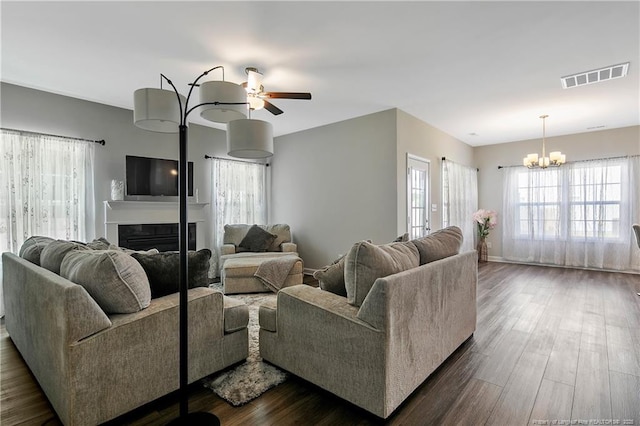 living room with dark hardwood / wood-style flooring and ceiling fan with notable chandelier