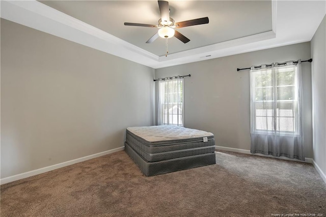 carpeted bedroom with ceiling fan and a tray ceiling