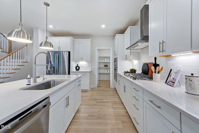 kitchen featuring decorative backsplash, appliances with stainless steel finishes, wall chimney range hood, and white cabinetry