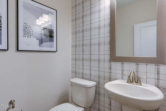 bathroom with sink, tile walls, and toilet