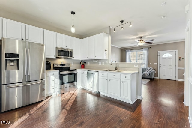 kitchen with white cabinets, decorative light fixtures, stainless steel appliances, sink, and kitchen peninsula