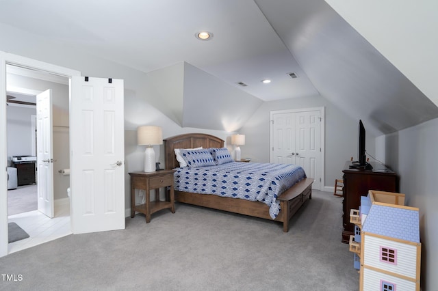 carpeted bedroom featuring ensuite bathroom, a closet, and vaulted ceiling