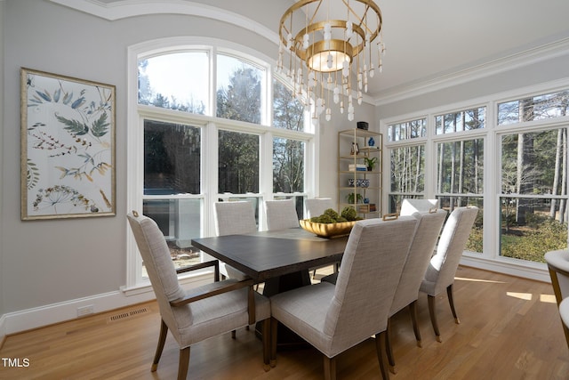 dining space featuring a wealth of natural light, a chandelier, ornamental molding, and light hardwood / wood-style flooring