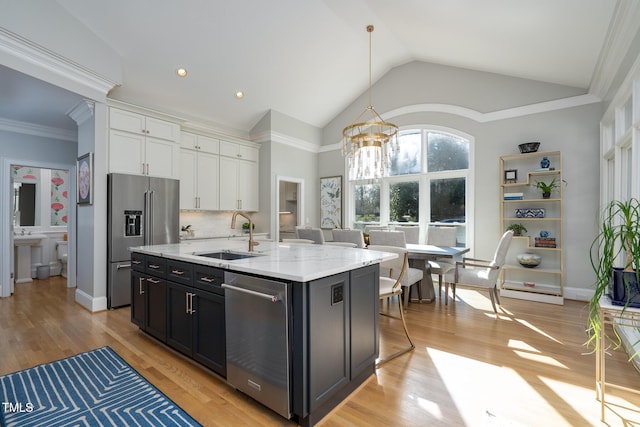 kitchen featuring white cabinetry, a center island with sink, stainless steel appliances, vaulted ceiling, and sink