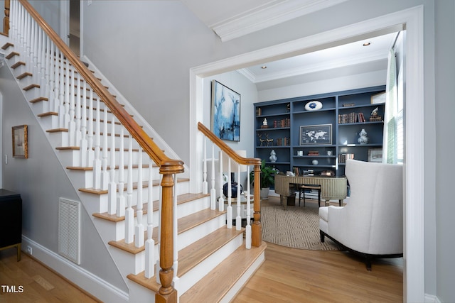 stairs featuring hardwood / wood-style flooring, built in features, and ornamental molding