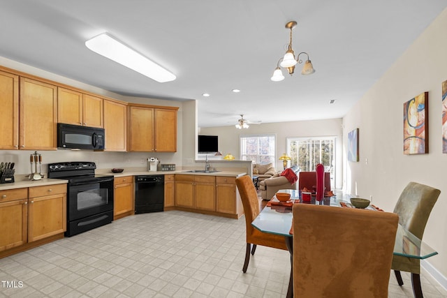 kitchen featuring ceiling fan with notable chandelier, black appliances, sink, hanging light fixtures, and kitchen peninsula