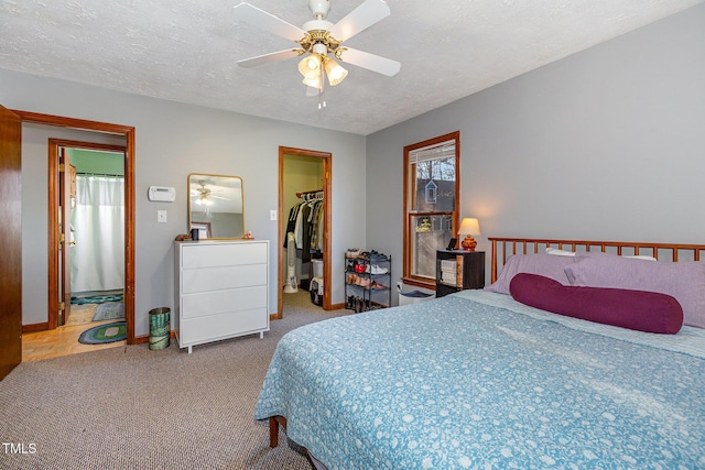 carpeted bedroom with ceiling fan, a closet, a spacious closet, and a textured ceiling