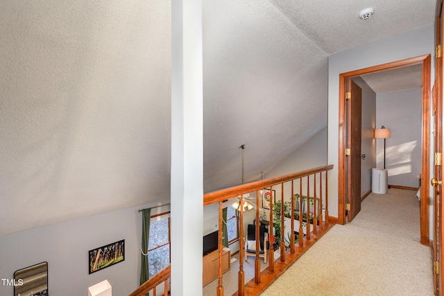 hallway with carpet, a textured ceiling, and lofted ceiling