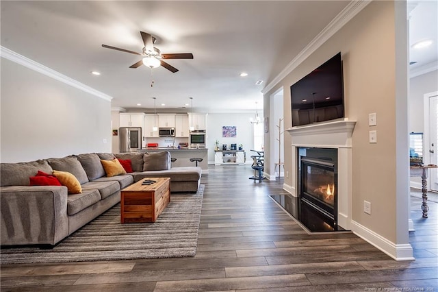 living room featuring ceiling fan with notable chandelier, dark wood-type flooring, and ornamental molding