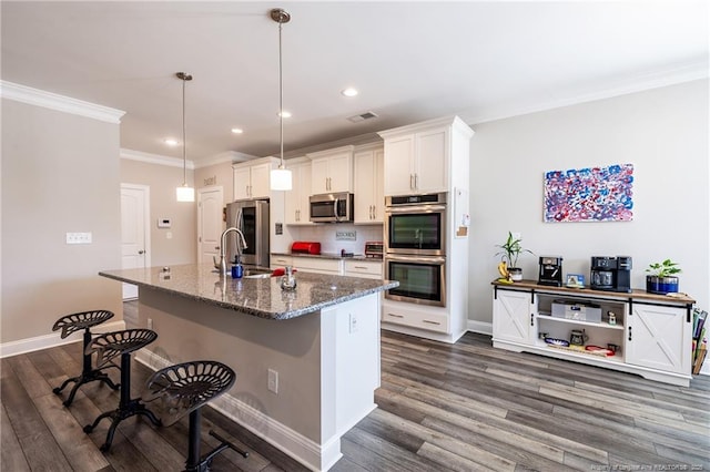 kitchen featuring sink, dark stone countertops, hanging light fixtures, stainless steel appliances, and white cabinets