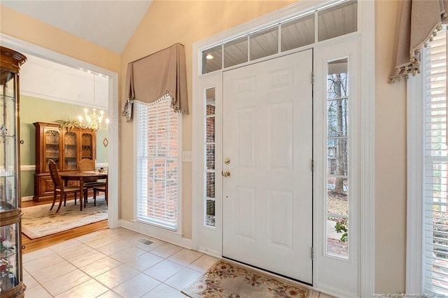 foyer with light tile patterned floors, lofted ceiling, and a chandelier