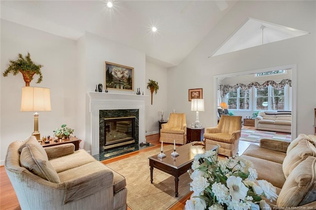 living room featuring a premium fireplace, light hardwood / wood-style floors, and high vaulted ceiling