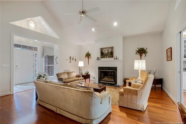 living room with a premium fireplace, ceiling fan, hardwood / wood-style floors, and high vaulted ceiling