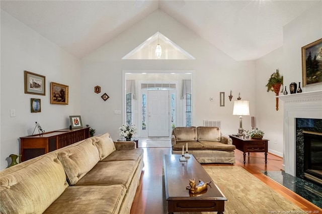 living room featuring a premium fireplace, lofted ceiling, and hardwood / wood-style floors