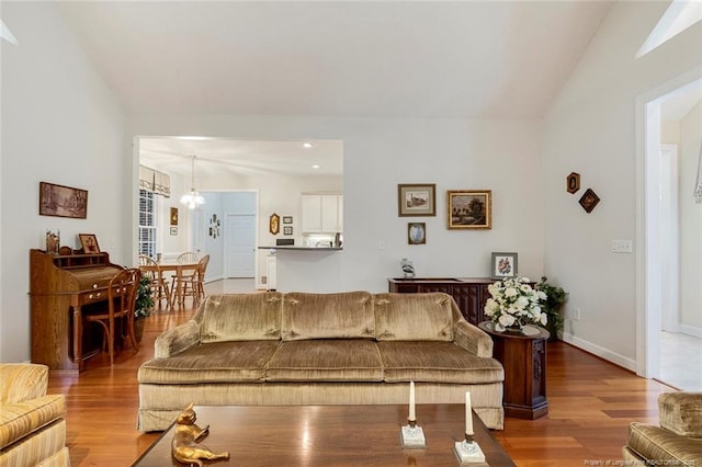 living room with light hardwood / wood-style floors, a chandelier, and vaulted ceiling