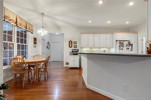 kitchen with white fridge, decorative light fixtures, dark wood-type flooring, a chandelier, and white cabinets