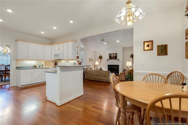 kitchen with tasteful backsplash, ceiling fan, light wood-type flooring, white cabinets, and range