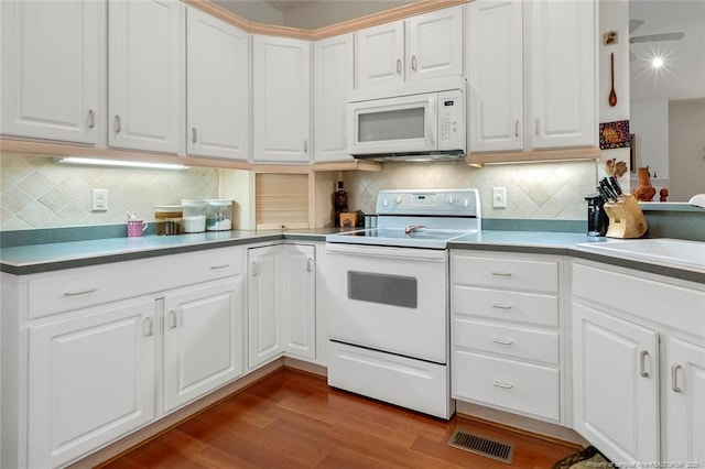 kitchen with white appliances, white cabinetry, and hardwood / wood-style flooring