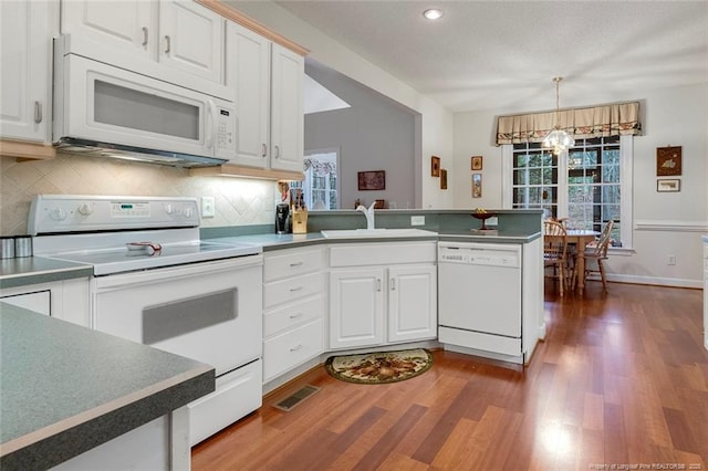 kitchen featuring white cabinetry, kitchen peninsula, a notable chandelier, white appliances, and dark hardwood / wood-style flooring