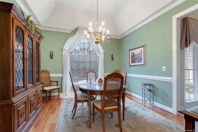 dining room featuring vaulted ceiling, crown molding, a chandelier, and light hardwood / wood-style flooring